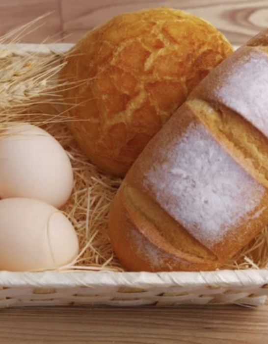 Ein mit Brot und Eiern gefüllter Korb auf einem Holztisch.