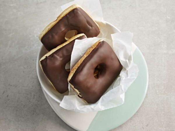 drei mit Schokolade überzogene Donuts auf einem Teller.