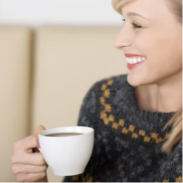 Eine Frau, die auf einer Couch sitzt und eine Tasse Kaffee hält.